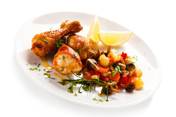 Grilled chicken drumsticks with vegetables on white background