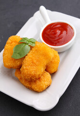 Chicken nuggets with tomato sauce decorated with basil in a white plate