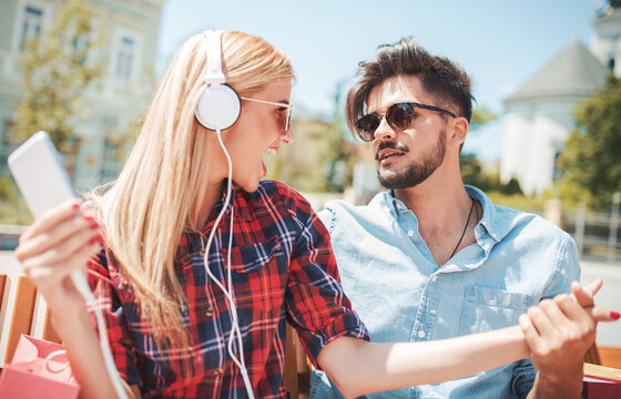 Young smiling couple listening to music with mobile phone and headphones. Dating, love and tenderness, lifestyle concept