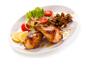 Grilled chicken drumsticks with vegetables on white background
