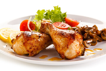 Grilled chicken drumsticks with vegetables on white background