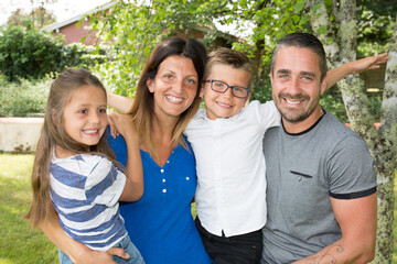 Portrait of happy family of four sitting on home garden park