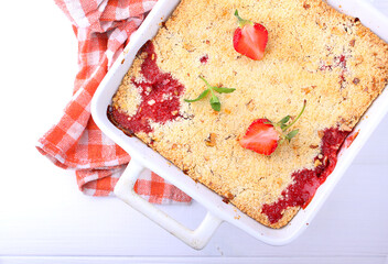 crumble with strawberries in white plate on a white background