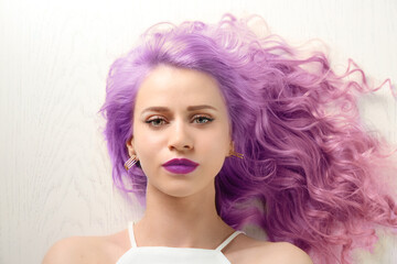 Lilac color for trendy hairstyle ideas. Young woman with dyed hair on white wooden background