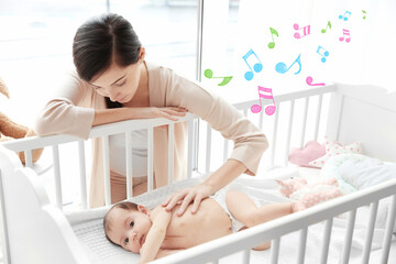 Happy mother with cute little baby lying in bed