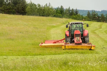 Foto op Plexiglas Work on an agricultural farm. A red tractor cuts a meadow.   © martinfredy