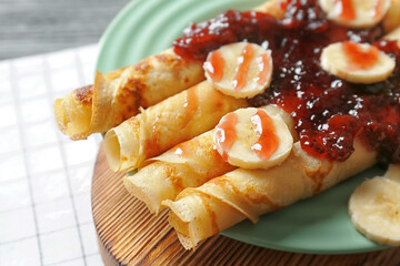 Tasty pancakes with jam and bananas on plate