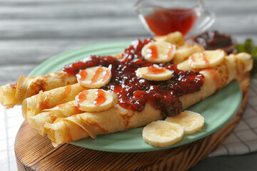 Tasty pancakes with jam and bananas on plate