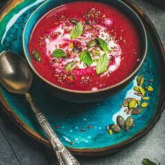 Spring detox beetroot soup with mint, chia, flax and pumpkin seeds in blue ceramic bowl over grey concrete background, square crop. Dieting, clean eating, vegan, vegetarian, weight loss food concept