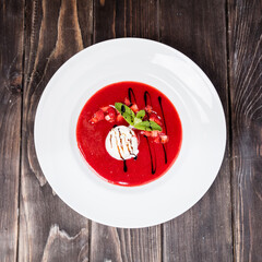One ice cream ball in strawberry sauce and mint, On a wooden table, country style
