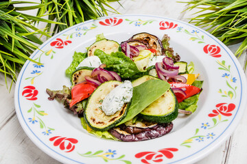 Spring salad with zucchini eggplant and cheese, on a wooden country style table