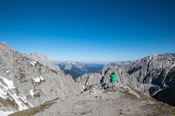 Ein Wanderer sitzt auf dem Berg und blickt in die Ferne
