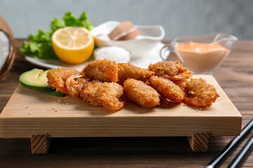 Wooden board with delicious coconut shrimps on table