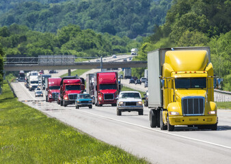 A yellow semi leads a packed line of traffic down an interstate in Tennessee.  Heat rising from the...