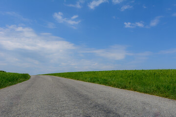 Strasse mit grünem Feld und blauem Himmel