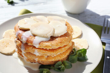 Delicious homemade coconut pancakes with sweet sauce and sliced banana on plate