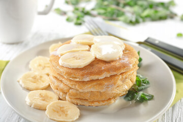 Delicious homemade coconut pancakes with sweet sauce and sliced banana on plate