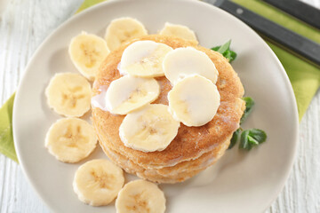Delicious homemade coconut pancakes with sweet sauce and sliced banana on plate