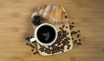 Delicious fresh croissants with fruit jam and coffee on wooden