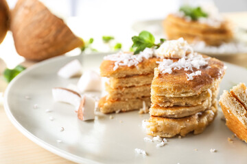 Plate with tasty homemade coconut pancakes and mint on table