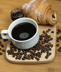 Delicious fresh croissants with fruit jam and coffee on wooden