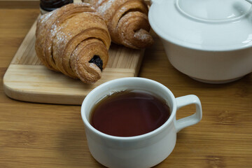 Delicious fresh croissants with fruit jam and tea on wooden