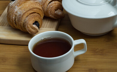 Delicious fresh croissants with fruit jam and tea on wooden