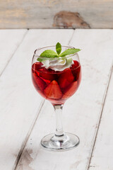 Strawberry jelly, strawberry and ice cream with mint in a glass on a wooden table, country style