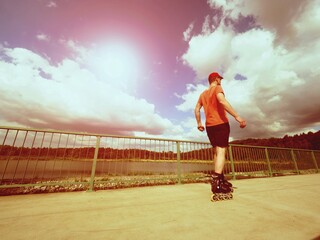 Vintage tone filter effect color style. Sportsman  with inline skates ride in summer park
