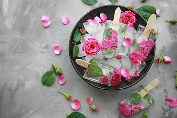 Black bowl with flower popsicles on gray background