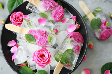 Black bowl with flower popsicles on gray background