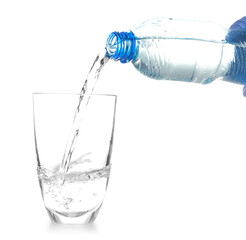 Water pouring from bottle into glass on white background