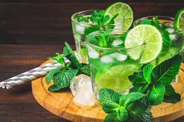 Mojito with mint and lime in a glass and a jug on the round boar