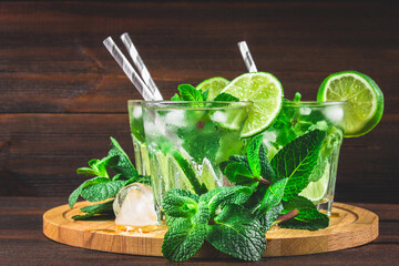 Mojito with mint and lime in a glass and a jug on the round boar