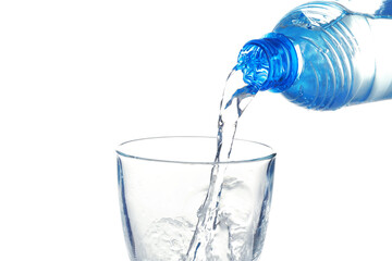 Water pouring from bottle into glass on white background