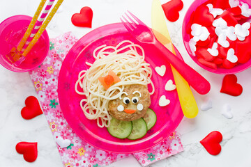 Creative idea for kids dinner, cute girl face from pasta, meatballs and vegetables