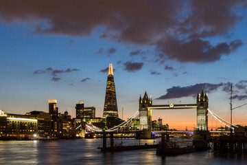 Tower Bridge, the Shard, city hall and business district in the background at night, London, Uk. © daliu