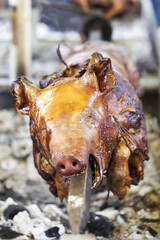 Traditionally suckling pig on a rotating spit with fire and smoke