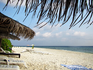Fototapeta na wymiar Beach of the island Ukulhas - perfect for relaxing with sunshade and sun lounger at the Maldives