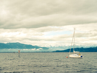 Fototapeta na wymiar Sailing Boat on lake Constance with dramatic sky and Swiss Alps in Background