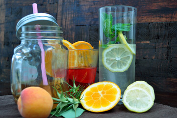 Glasses with refreshing drinks with fruits and herbs on an old wooden background