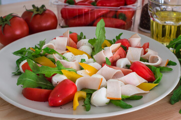 Summer salad with turkey breast, greens, tomato and mozzarella. Wooden background. Top view. Close-up