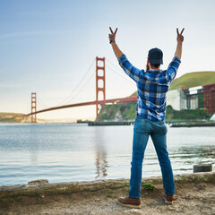 Fototapeta na wymiar man with arms up making peace sign by the golden gate bridge in san francisco