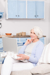 Grandmother chatting with relatives on skype. Pretty grandmother using laptop computer for special purposes at home.