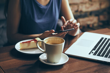woman with phone and cup of coffee, laptop