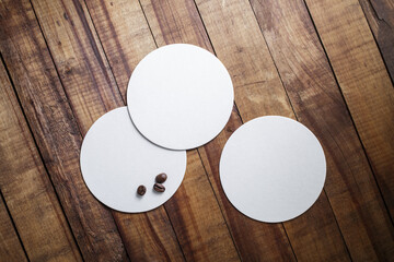 Blank square beer coasters and coffee beans on vintage wood table background. Top view.
