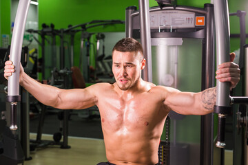 Fototapeta na wymiar Strong muscular handsome man exercising at the gym