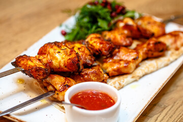 Chicken kebab with tomato sauce, herbs and pomegranate seeds.