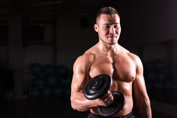 Naklejka na ściany i meble Portrait of strong healthy handsome Athletic Man Fitness Model posing with a dumbbell.
