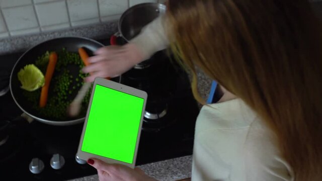 Young woman searching the recipe on the tablet in the kitchen. Top view. Close-up. Green screen
